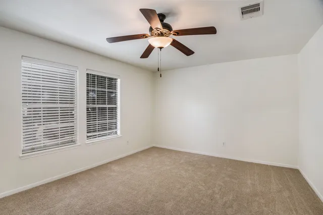 an empty room with windows and fan