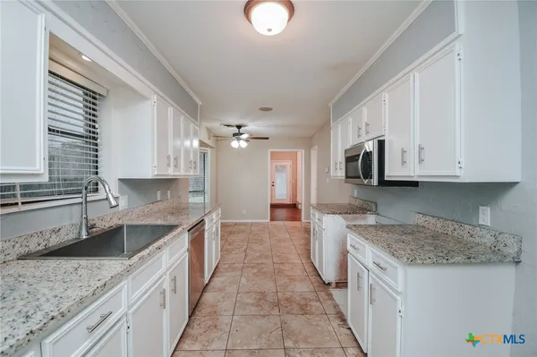 a kitchen with granite countertop a sink stove and cabinets