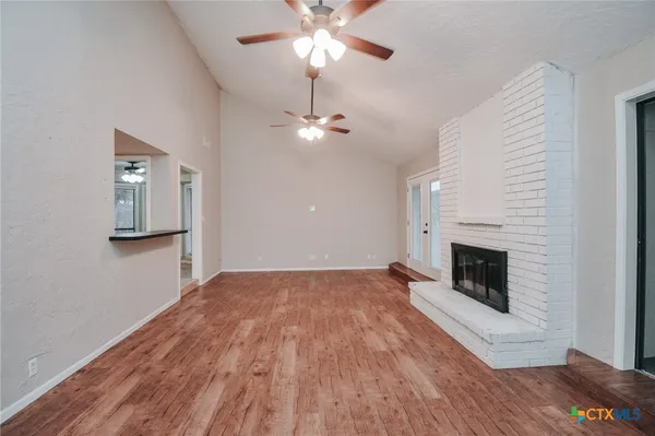 a view of empty room with wooden floor and fireplace
