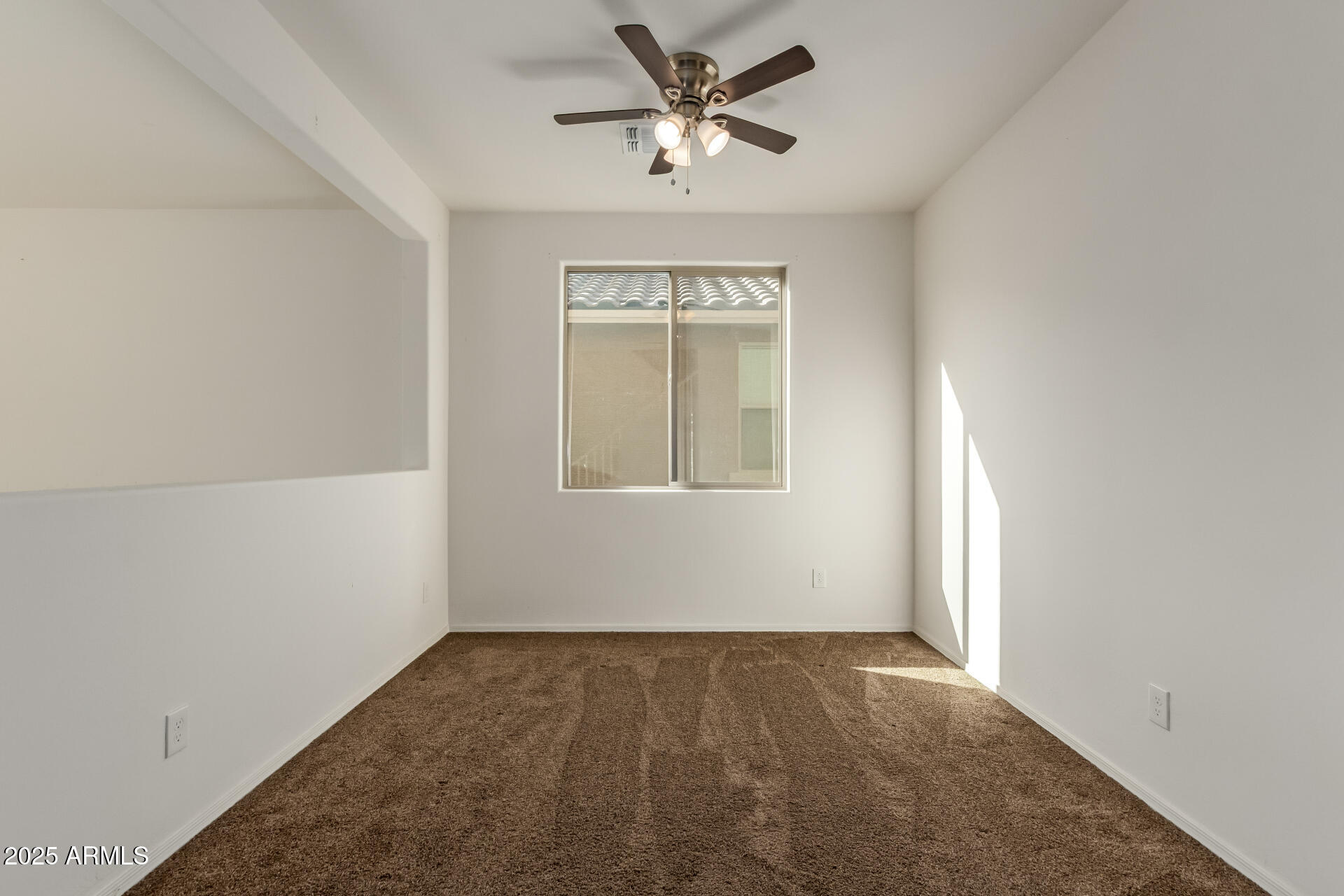 11603 West Calavar Road El Mirage, AZ 85335 - Photo 35 of 38 an empty room with a window and a ceiling fan