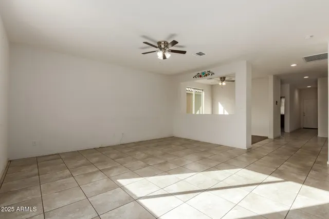an empty room with windows and ceiling fan