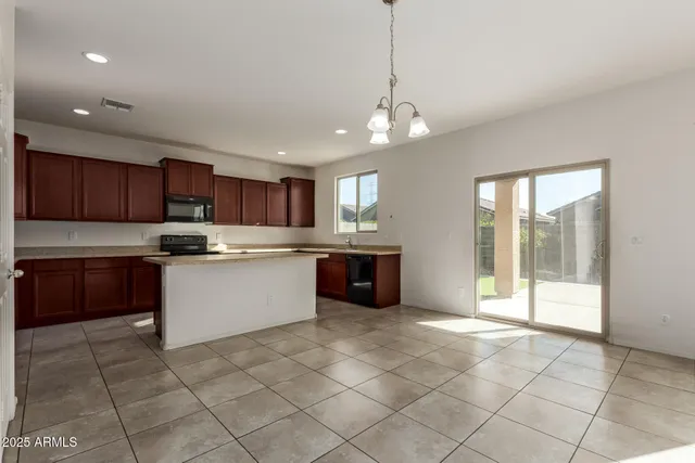 a large kitchen with stainless steel appliances granite countertop a stove a sink a counter top space and cabinets