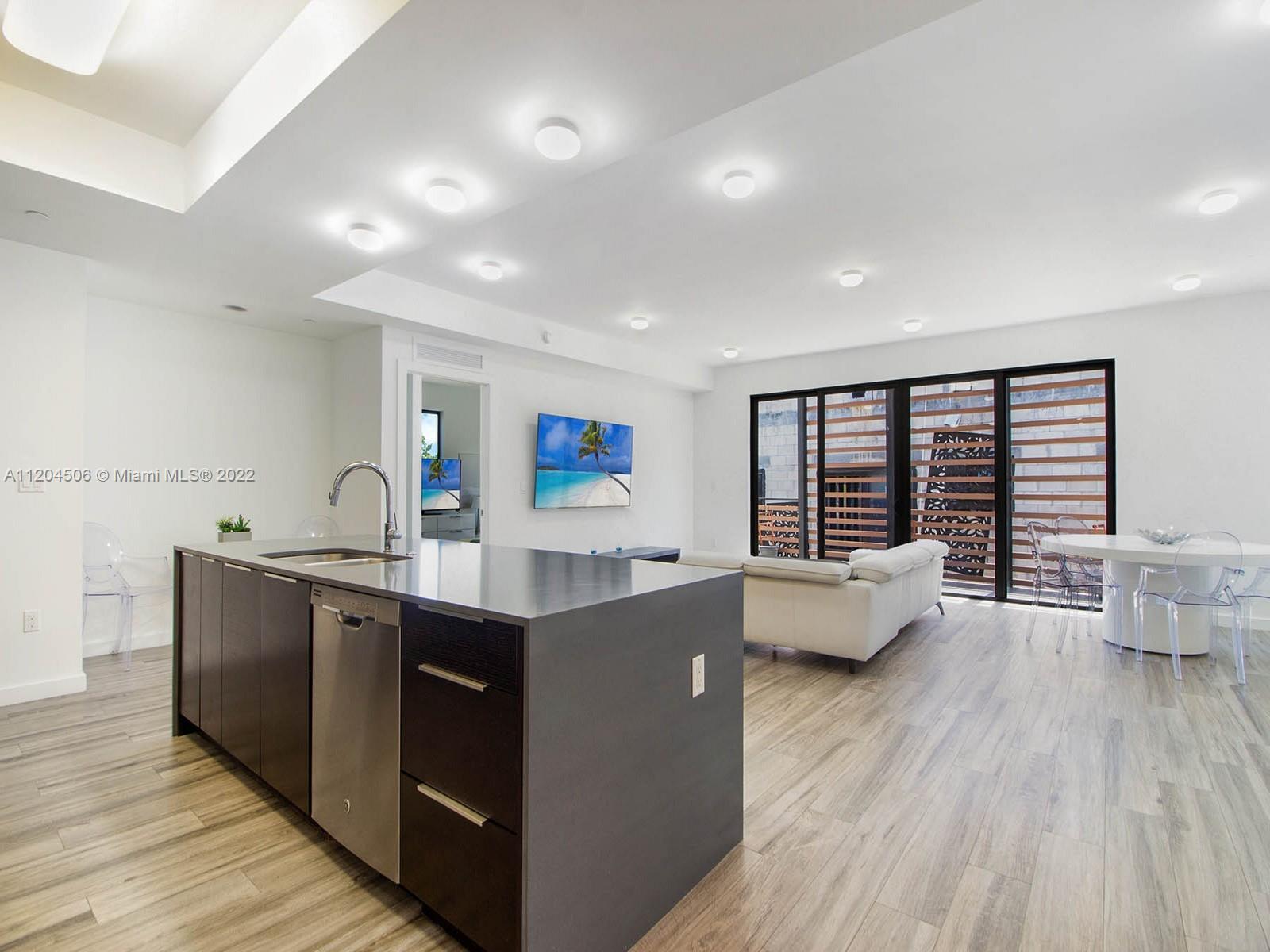 2955 Bird Avenue, Unit PHA Miami, FL 33133 - Photo 3 of 33 a large kitchen with stainless steel appliances a large counter top a sink and a wooden floor