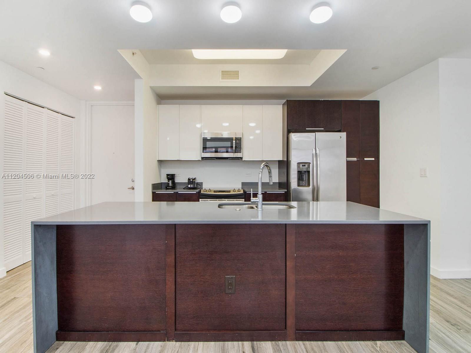 2955 Bird Avenue, Unit PHA Miami, FL 33133 - Photo 6 of 33 a kitchen with kitchen island granite countertop a sink cabinets and stainless steel appliances