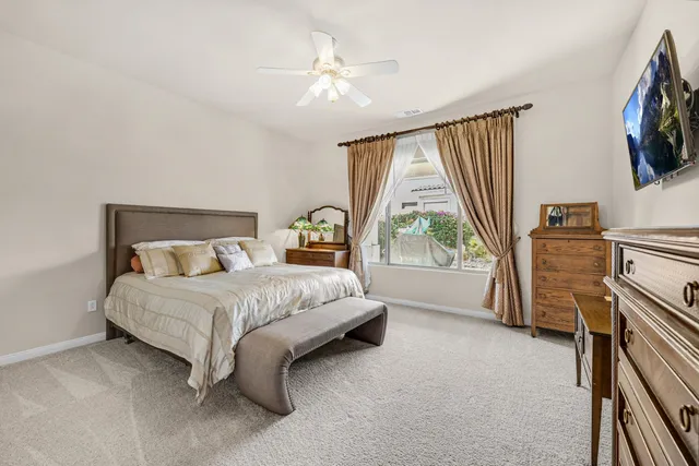 a spacious bedroom with a bed flat screen tv and a large window