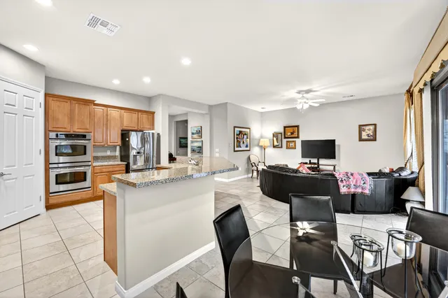 a living room with stainless steel appliances kitchen island granite countertop a table and chairs in it