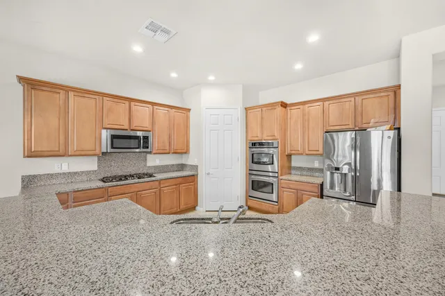 a kitchen with stainless steel appliances granite countertop a refrigerator and a stove top oven