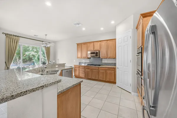 a kitchen with stainless steel appliances granite countertop a refrigerator a sink a stove a washer and dryer with wooden floor