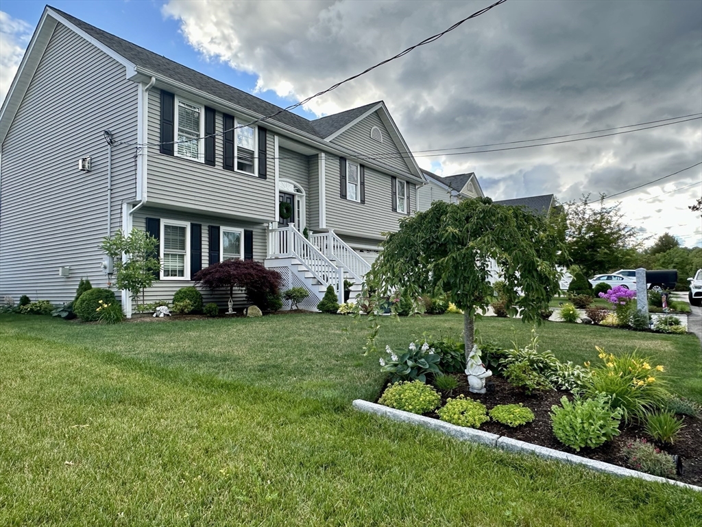 115 Bronson Fall River Fall River, MA 02724 - Photo 3 of 37 a front view of a house with a garden and trees