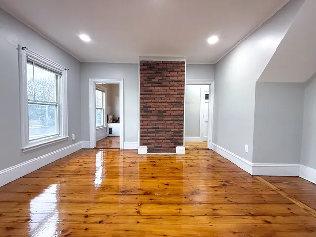 a view of an empty room with window and wooden floor