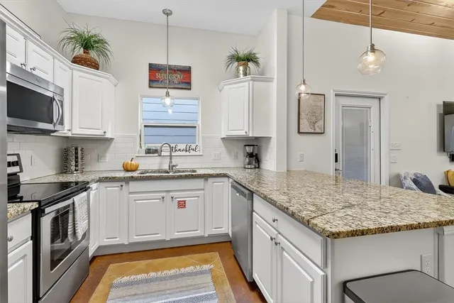 a kitchen with granite countertop stainless steel appliances a sink stove and microwave