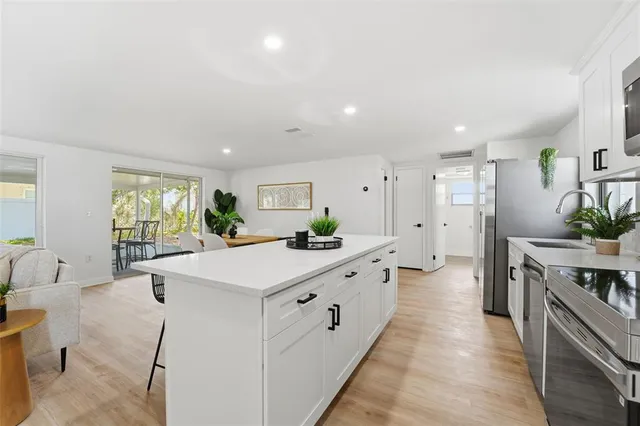 a large kitchen with kitchen island a large counter top space a sink stainless steel appliances and cabinets