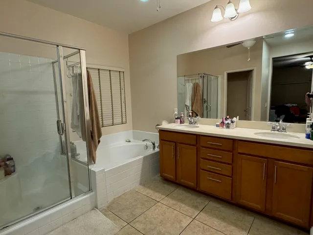 a bathroom with a double vanity sink a large mirror and shower