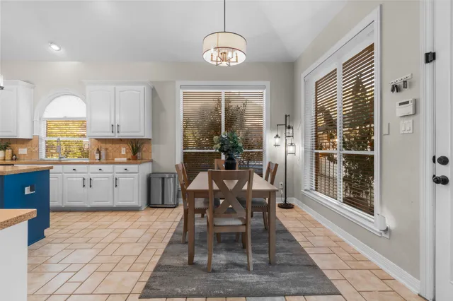 a dining hall with granite countertop a dining table chairs and large windows