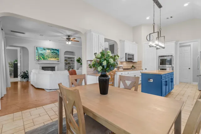 a kitchen with stainless steel appliances kitchen island granite countertop a refrigerator a sink dishwasher a dining table and chairs with wooden floor