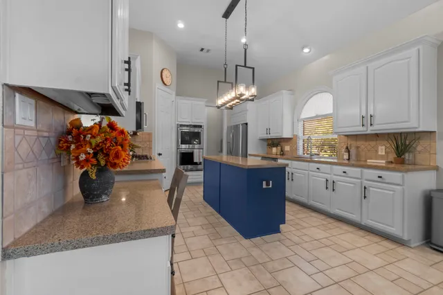 a kitchen with stainless steel appliances granite countertop a sink a stove and a wooden cabinets