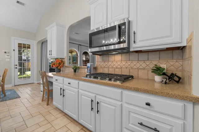 a kitchen with stainless steel appliances granite countertop white cabinets a stove a sink and dishwasher