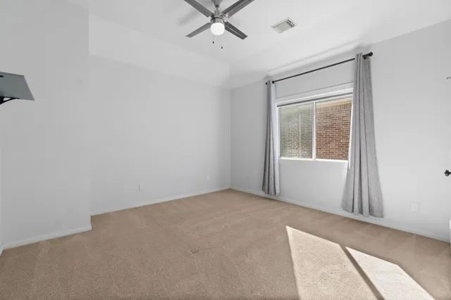 an empty room with a window and a fan