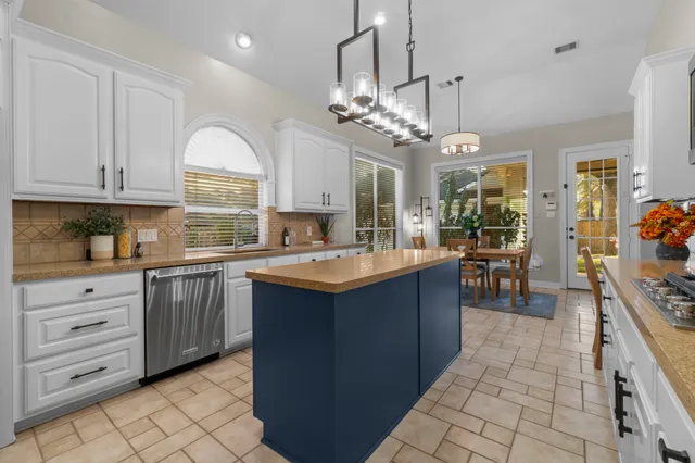 a kitchen with stainless steel appliances granite countertop a sink a stove top oven a kitchen island a counter top space and cabinets