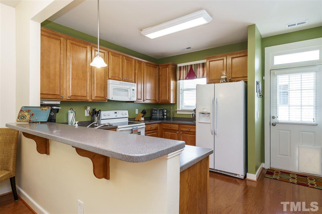 4422 Crystal Breeze Street Raleigh, NC 27614 - Photo 10 of 25 a kitchen with stainless steel appliances granite countertop a refrigerator a sink a stove a dining table and chairs with wooden floor