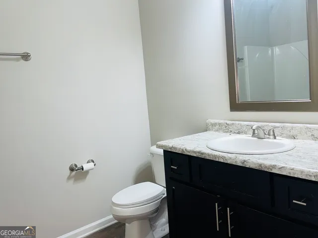 a bathroom with a granite countertop sink toilet and mirror