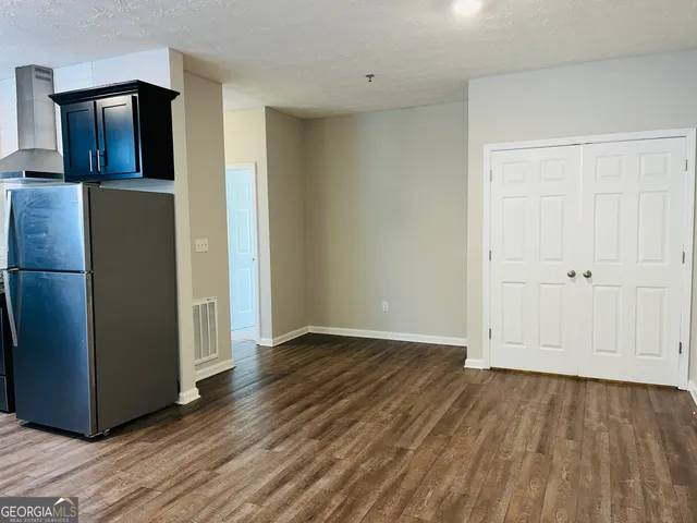 a view of an empty room with wooden floor and closet