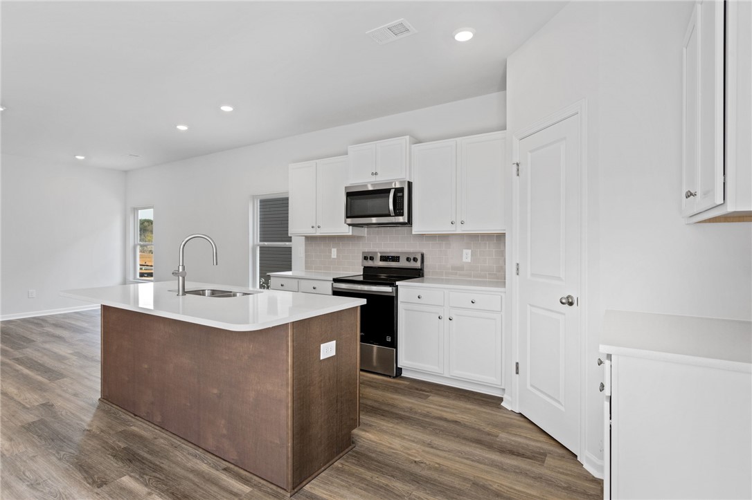 146 Cedar Shoals Easley, SC 29640 - Photo 11 of 34 This kitchen features a central island with a sink, white cabinetry, and modern appliances.