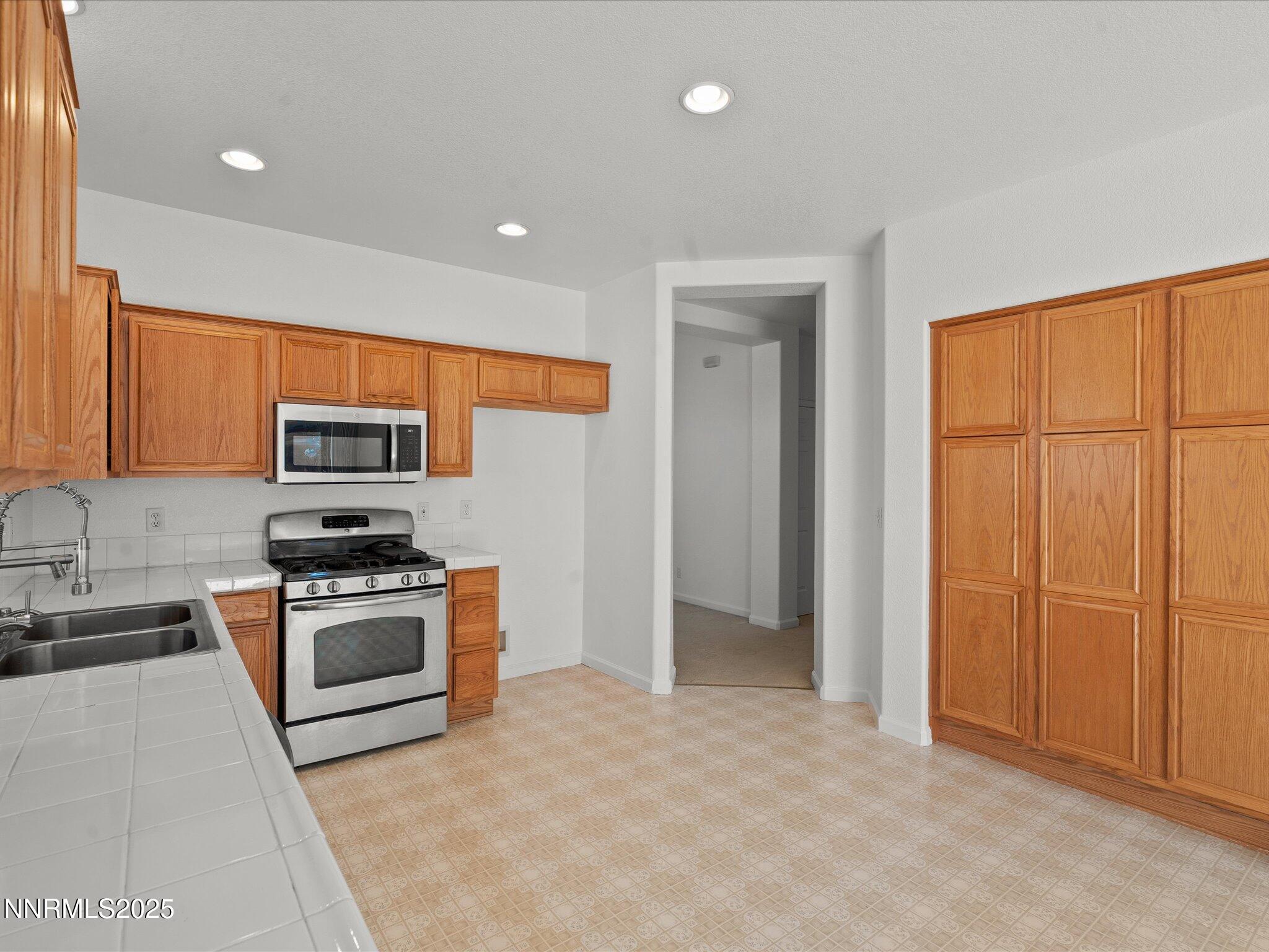 805 Sauvignon Drive Reno, NV 89506 - Photo 12 of 56 a kitchen with stainless steel appliances granite countertop a stove a sink and a refrigerator with white cabinets