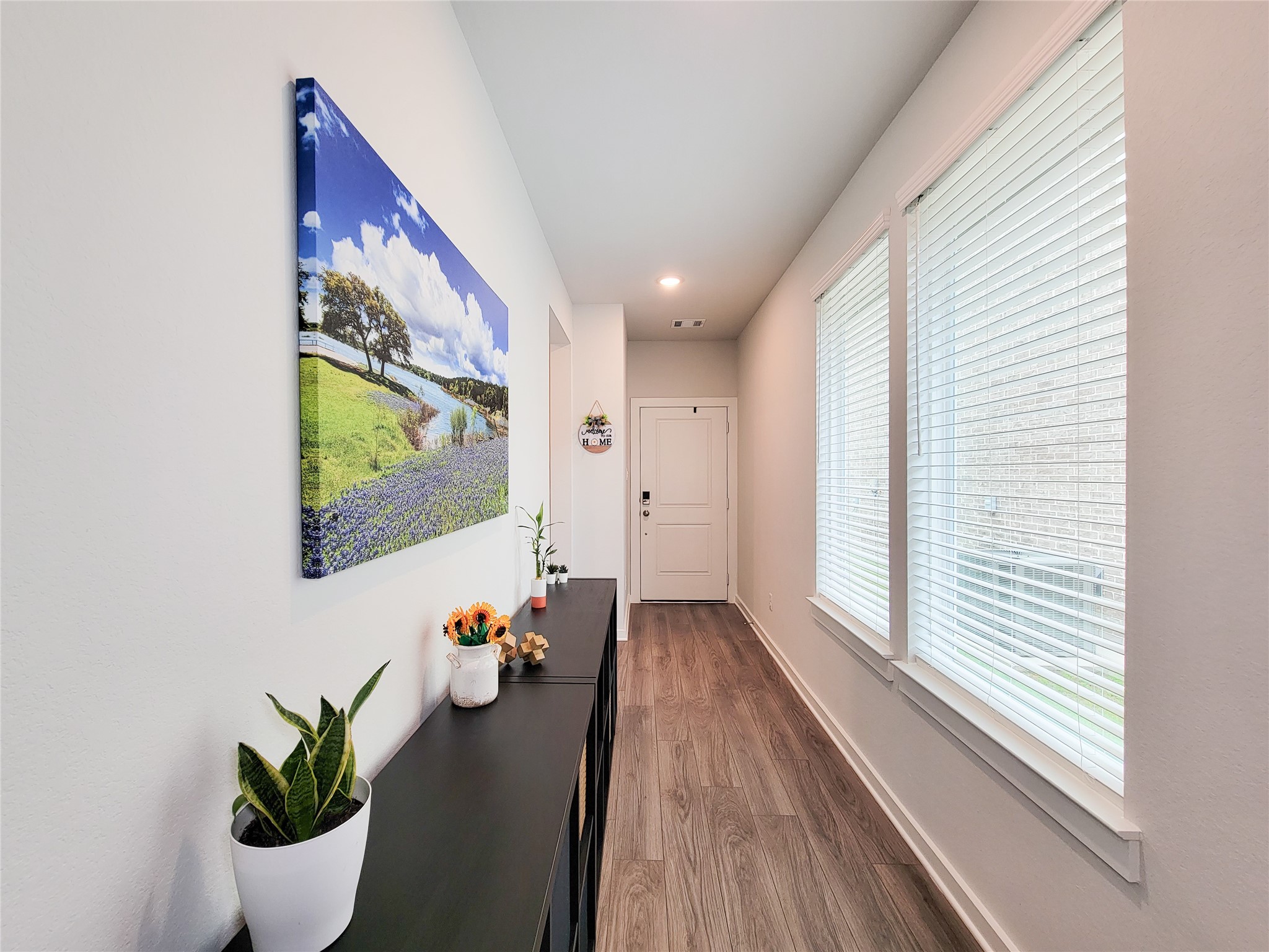 2818 Bluebonnet Ridge Drive Conroe, TX 77304 - Photo 8 of 42 a hallway with wooden floor and a potted plant