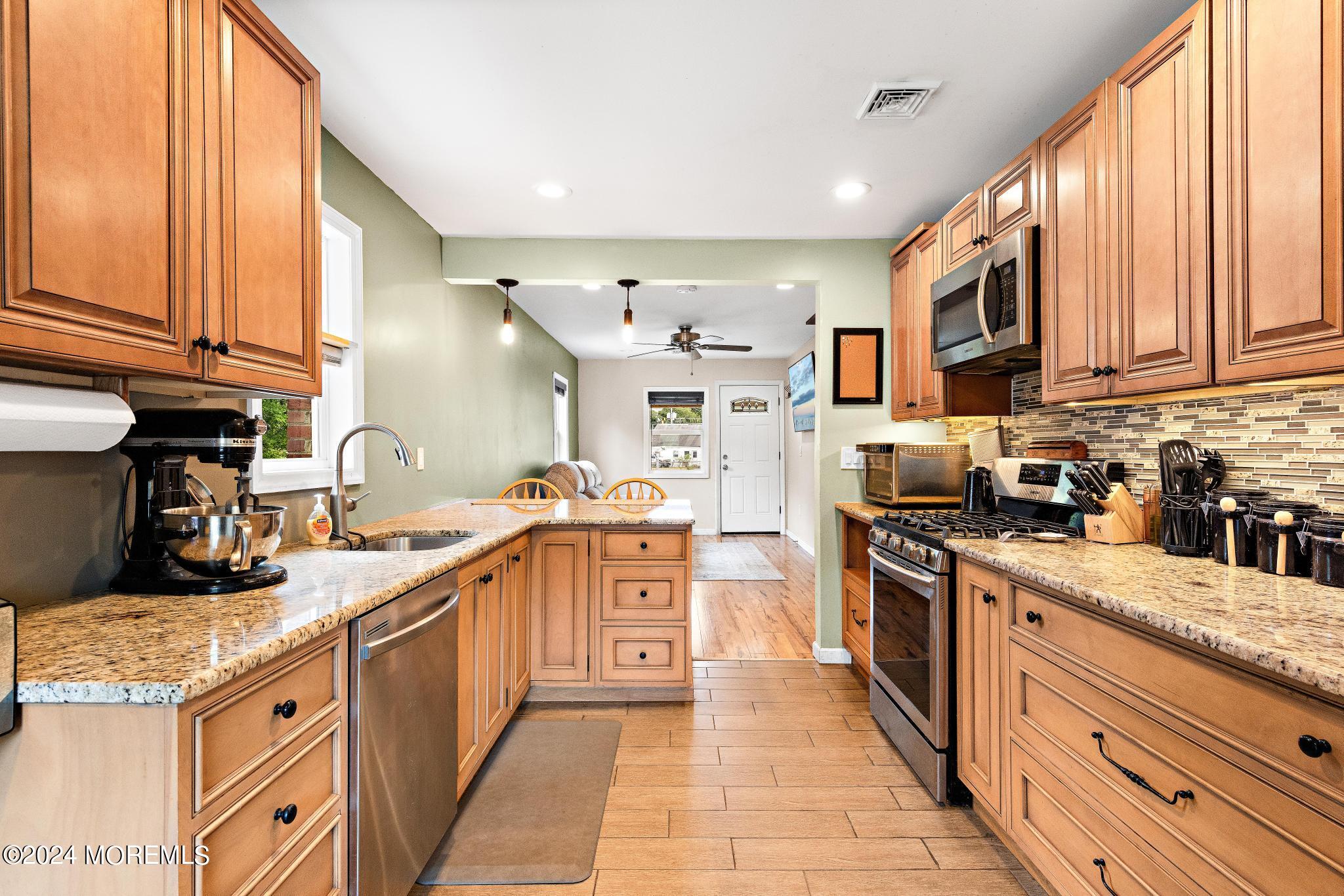 a large kitchen with stainless steel appliances granite countertop a stove a sink dishwasher and a refrigerator