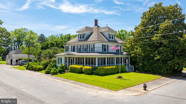 a view of a white house with a yard and potted plants