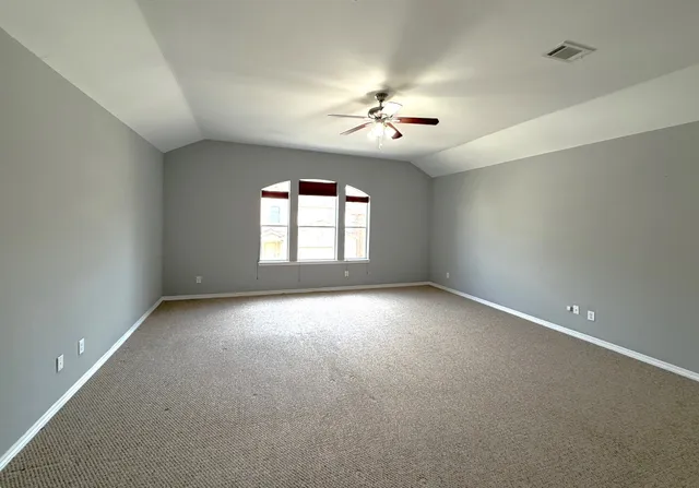 an empty room with a ceiling fan and window