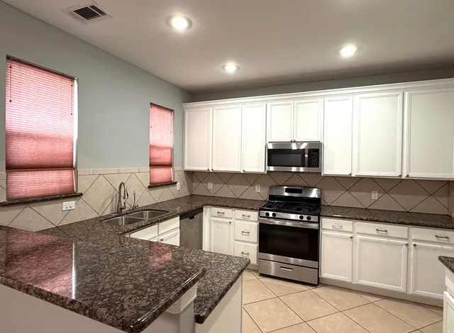 a kitchen with stainless steel appliances granite countertop a sink stove and microwave