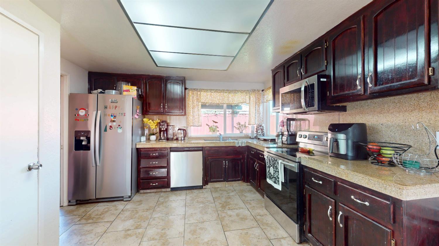 4005 Honey Creek Road Modesto, CA 95356 - Photo 13 of 25 a large kitchen with stainless steel appliances granite countertop a stove refrigerator a sink dishwasher and cabinets with wooden floor