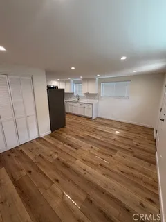 a view of kitchen and empty room with wooden floor