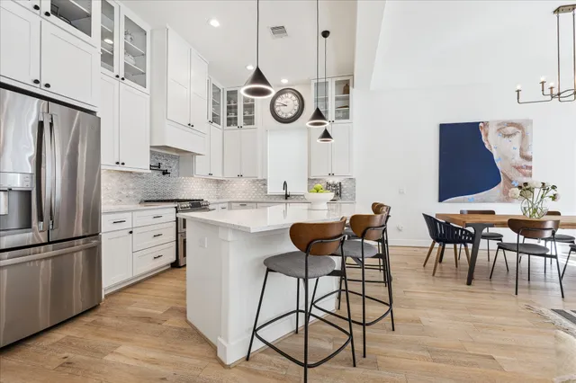 a kitchen with stainless steel appliances granite countertop a refrigerator a stove and white cabinets with wooden floors