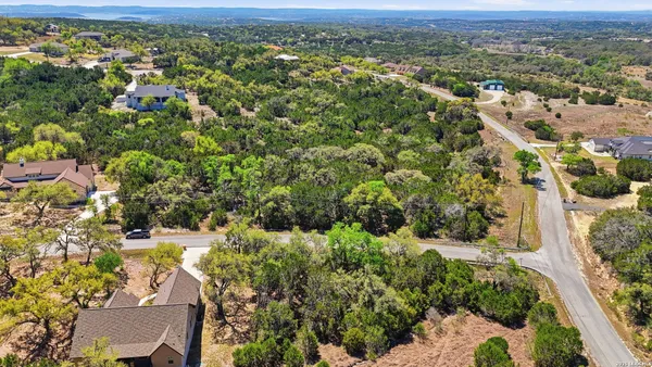 an aerial view of residential houses with outdoor space and trees