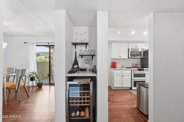 a kitchen with stainless steel appliances kitchen island granite countertop a refrigerator a stove and white cabinets with wooden floor