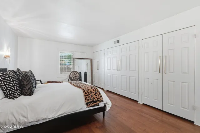 a bedroom with a bed a table and wooden floor