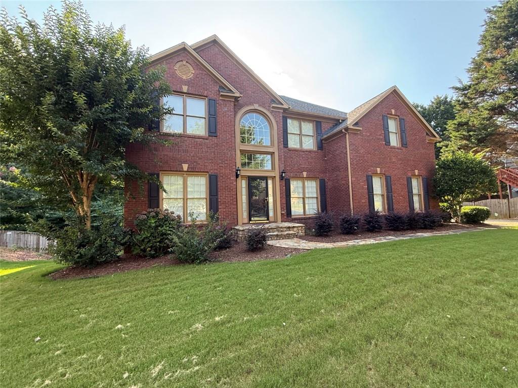 a front view of a house with garden and trees