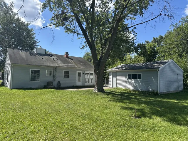 a house that is sitting in the grass with tress in the background