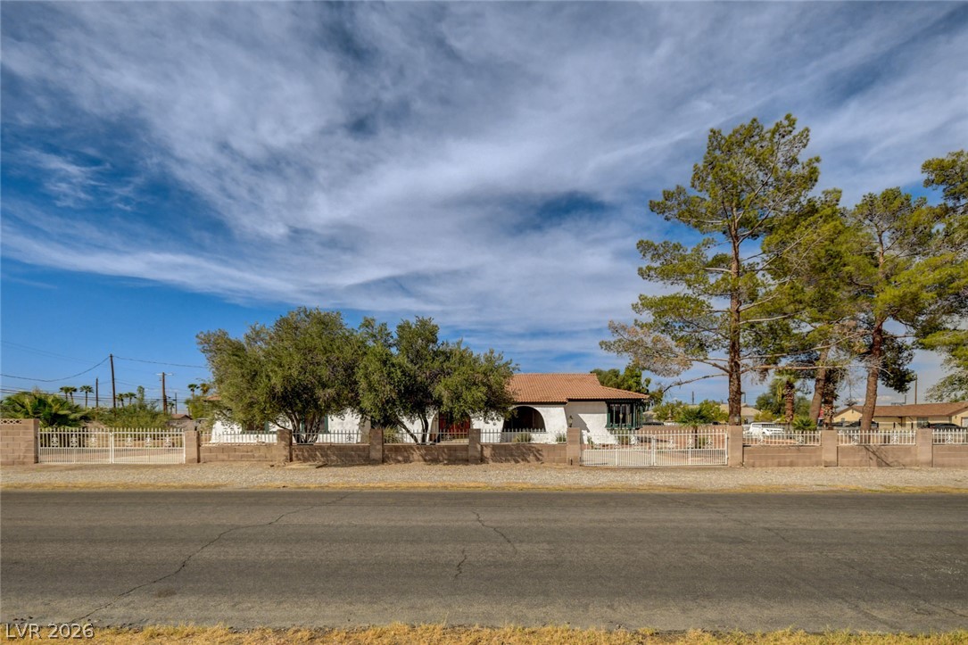 1401 Sharon Road Las Vegas, NV 89106 - Photo 4 of 73 Gated Spanish-style architecture framed by mature trees stands proudly along the paved streetscape.