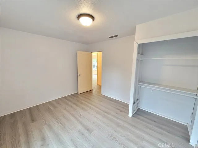 an empty room with wooden floor & closet area