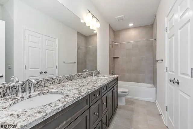 a bathroom with a granite countertop sink a toilet and shower