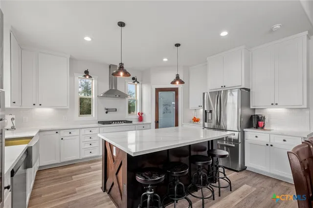 a kitchen with a sink a center island stainless steel appliances and cabinets