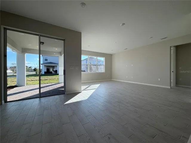 an empty room with floor to ceiling window and wooden floor