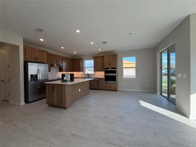 a large kitchen with a refrigerator and a stove top oven