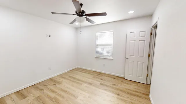 an empty room with a window and a fan