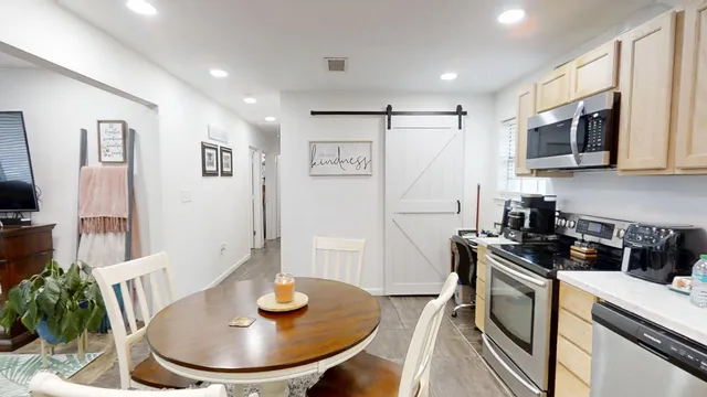 a kitchen with stainless steel appliances a microwave a stove a table and chairs