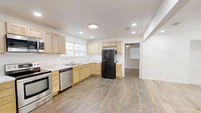 a kitchen with stainless steel appliances granite countertop a refrigerator a stove top oven a sink and dishwasher